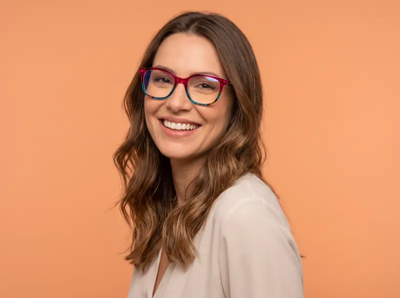 Mulher sorrindo com óculos coloridos da Ótica Prisma